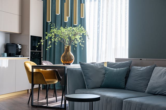 living-room-and-kitchen-with-white-cupboards-blue-couch-and-a-table